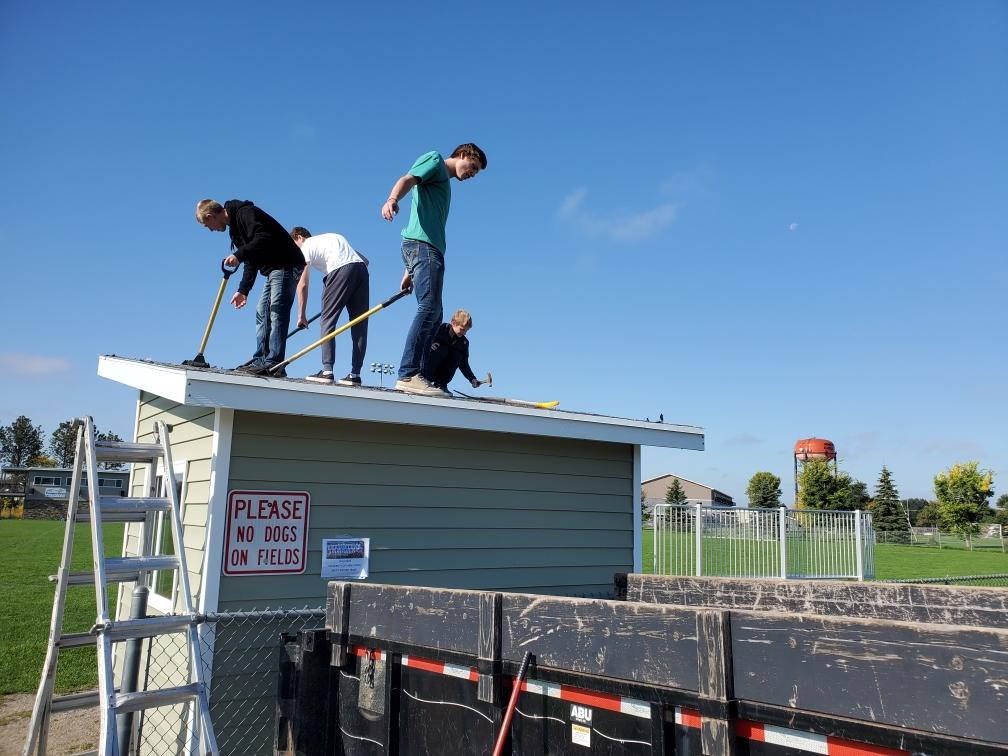Students working on the roof of a small building.